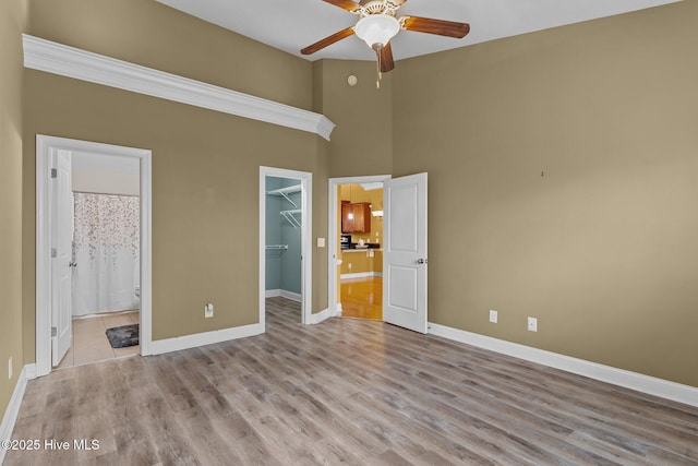 1036 Tideline Dr, Leland, NC 28451 - unfurnished bedroom featuring a walk in closet, a closet, wood finished floors, ensuite bathroom, and a towering ceiling