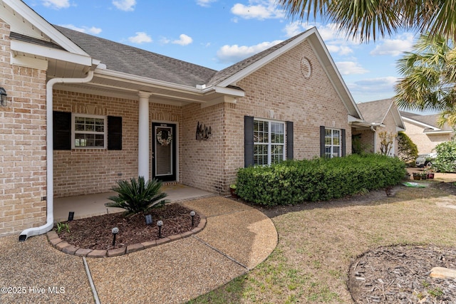 1036 Tideline Dr, Leland, NC 28451 - view of exterior entry with brick siding, roof with shingles, and a lawn
