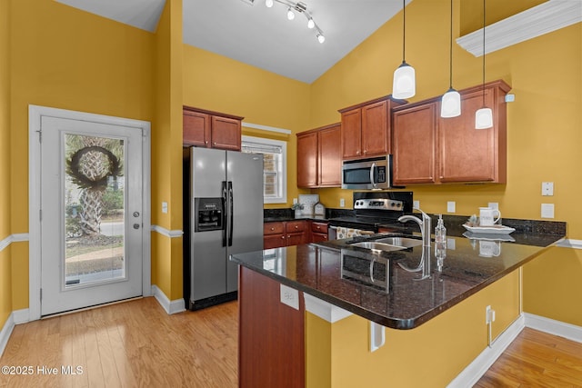 1036 Tideline Dr, Leland, NC 28451 - kitchen featuring stainless steel appliances, a peninsula, light wood-style floors, dark stone counters, and hanging light fixtures