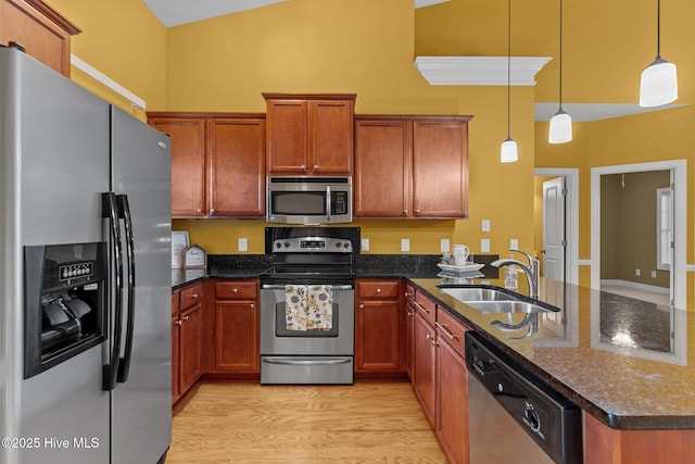 1036 Tideline Dr, Leland, NC 28451 - kitchen featuring appliances with stainless steel finishes, a peninsula, light wood-style floors, decorative light fixtures, and brown cabinets