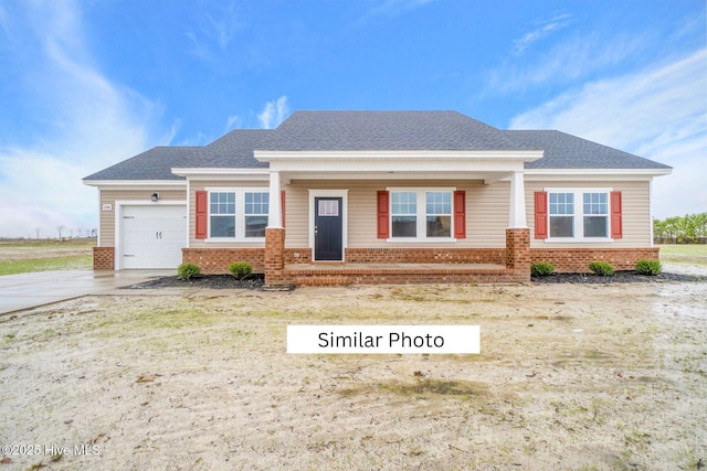 craftsman-style house with a garage, concrete driveway, brick siding, and roof with shingles