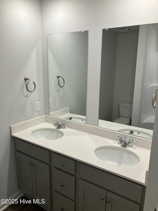 full bathroom with double vanity, toilet, and a sink