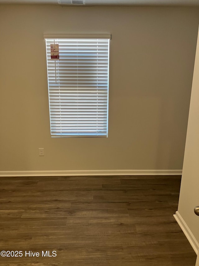 unfurnished room featuring visible vents, baseboards, and wood finished floors