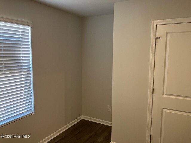 spare room featuring dark wood-type flooring and baseboards