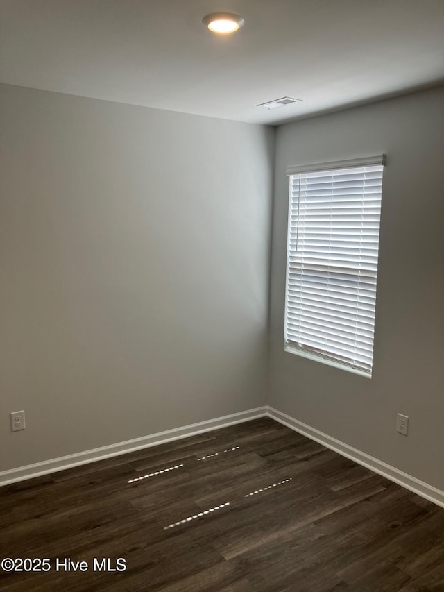 spare room with visible vents, wood finished floors, and baseboards