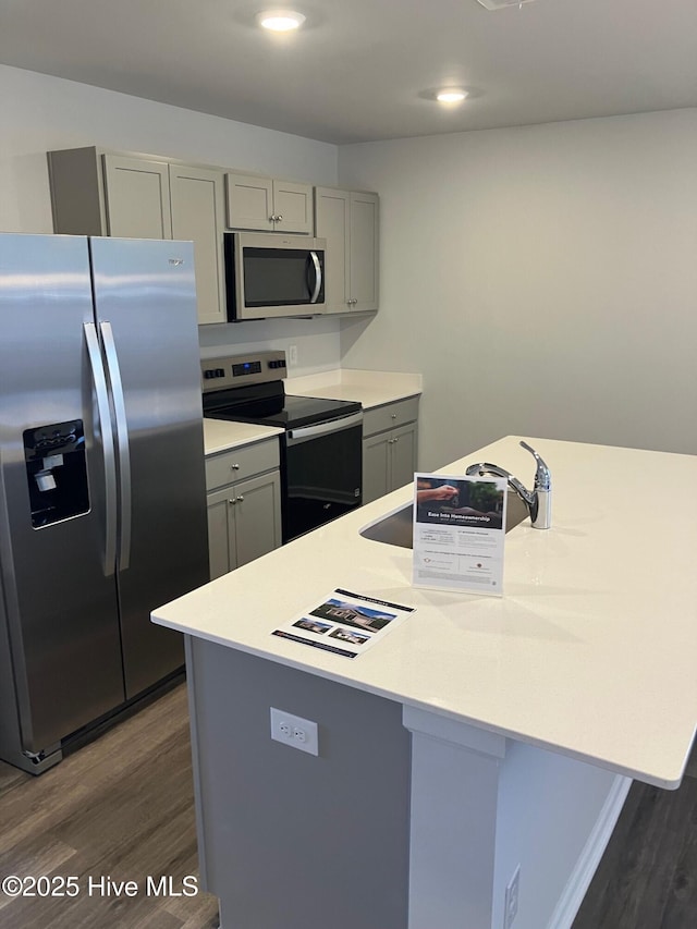 kitchen featuring dark wood-type flooring, appliances with stainless steel finishes, gray cabinets, and light countertops