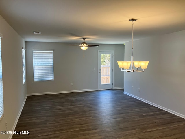 empty room featuring visible vents, baseboards, dark wood finished floors, and ceiling fan with notable chandelier