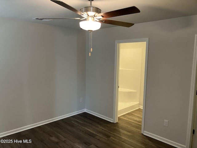 empty room featuring dark wood finished floors, a ceiling fan, and baseboards