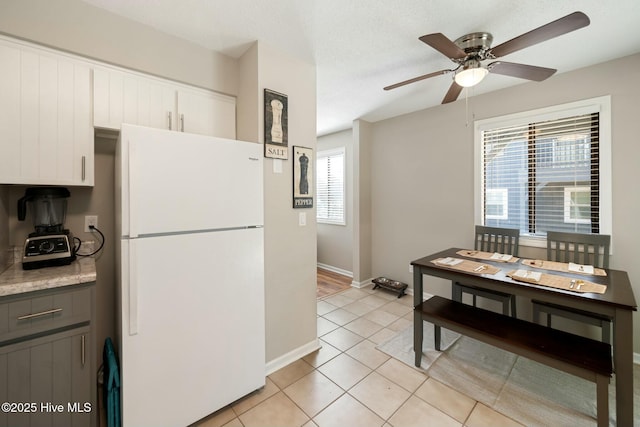 kitchen featuring gray cabinets, a ceiling fan, white cabinetry, freestanding refrigerator, and light tile patterned floors