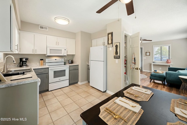 kitchen featuring visible vents, open floor plan, white appliances, a ceiling fan, and a sink