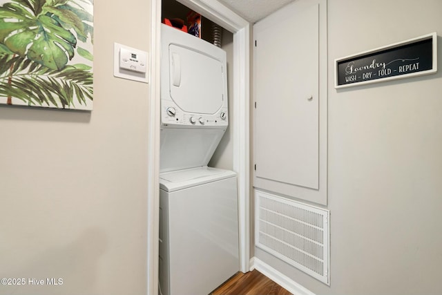 laundry room with laundry area, wood finished floors, visible vents, and stacked washer and dryer