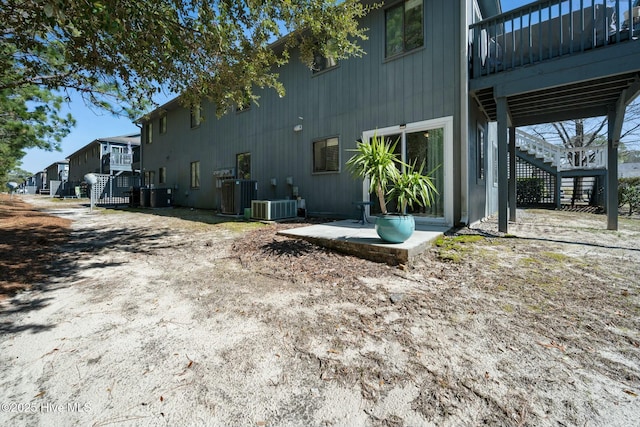 view of side of home with stairway, a patio, and central AC unit