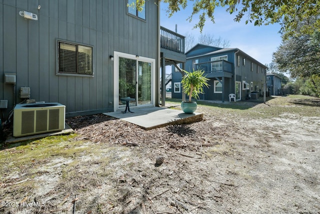 back of property with a patio area, board and batten siding, and central AC