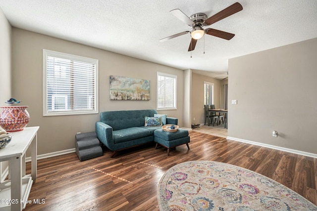 living area with a textured ceiling, a ceiling fan, and wood finished floors