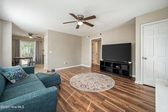 living room with baseboards, wood finished floors, visible vents, and ceiling fan