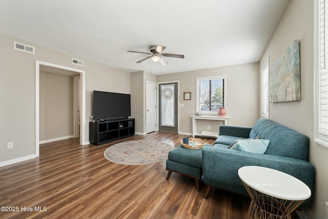 living area featuring visible vents, baseboards, a ceiling fan, and wood finished floors