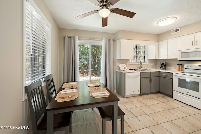 kitchen with white appliances, light tile patterned floors, visible vents, a sink, and light countertops