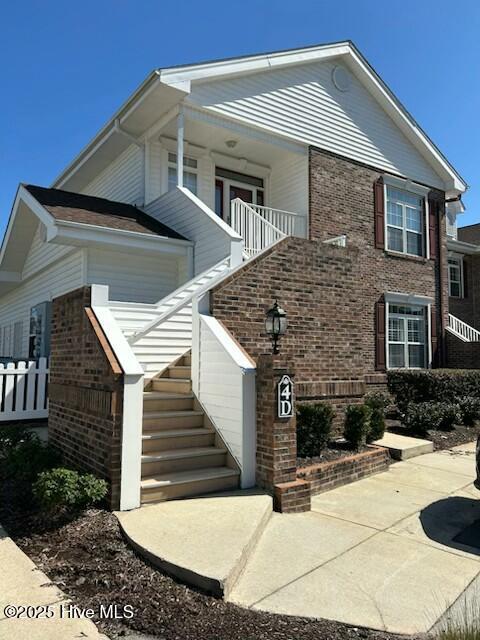 exterior space featuring brick siding and stairs