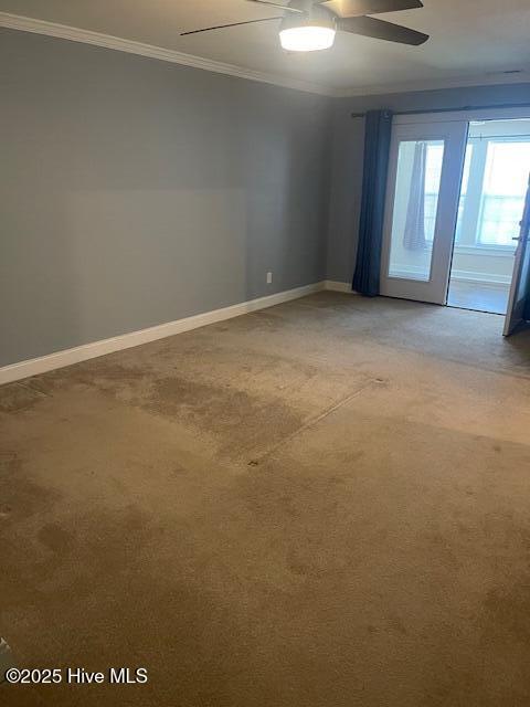 spare room with baseboards, ornamental molding, a ceiling fan, and light carpet