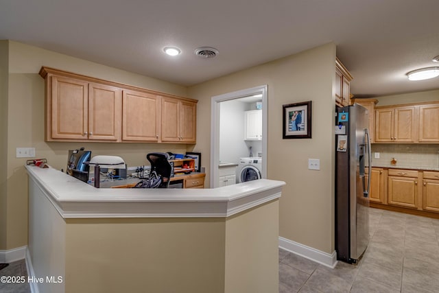 kitchen featuring stainless steel fridge, visible vents, washer / clothes dryer, light brown cabinetry, and backsplash