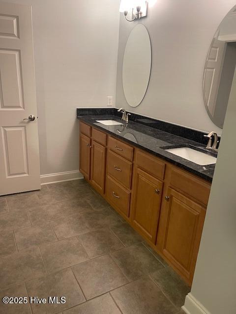 full bathroom with a sink, baseboards, and double vanity