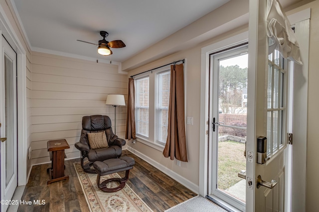 sitting room featuring a ceiling fan, baseboards, and dark wood-type flooring