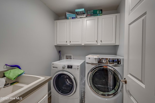 clothes washing area with a sink, cabinet space, and washer and dryer