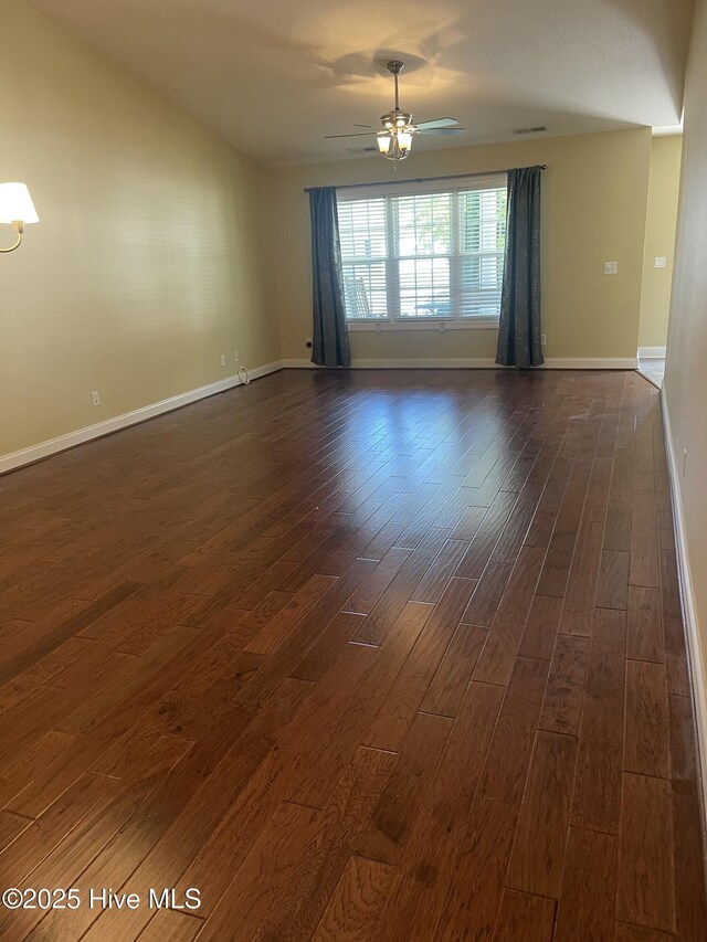 unfurnished room featuring dark wood-type flooring, a ceiling fan, baseboards, and visible vents