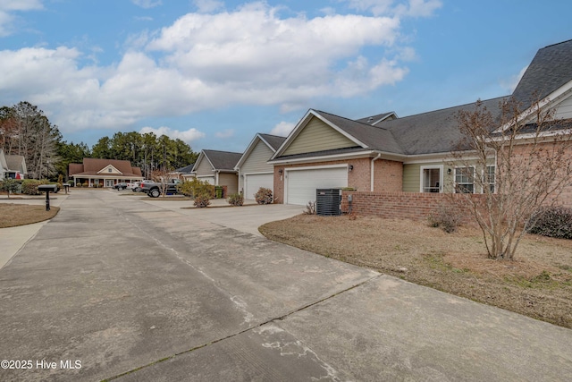 single story home with concrete driveway, brick siding, and an attached garage