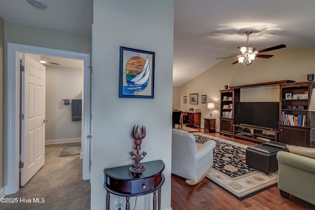 living room with a ceiling fan, vaulted ceiling, and wood finished floors