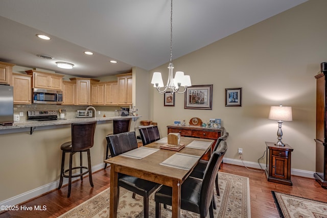 dining space featuring visible vents, baseboards, dark wood-style floors, an inviting chandelier, and vaulted ceiling