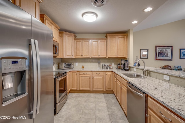 kitchen featuring appliances with stainless steel finishes, visible vents, a sink, and light brown cabinetry