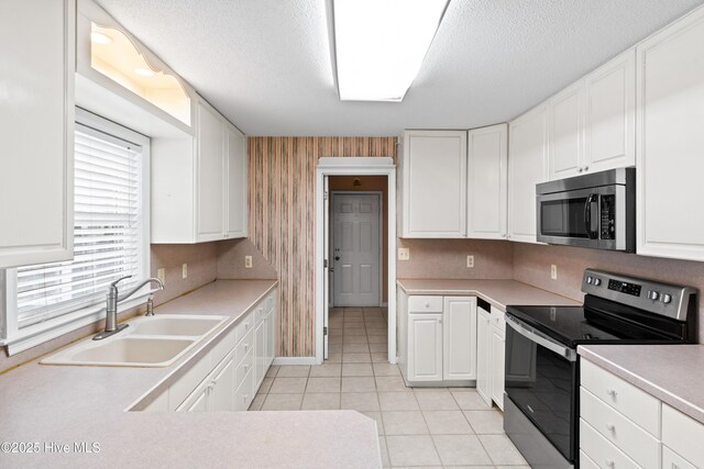 1611 Gores Landing Rd SW ., Unit Ocean Isle Beach, NC 28469 - kitchen with light tile patterned floors, white cabinets, a sink, and stainless steel appliances