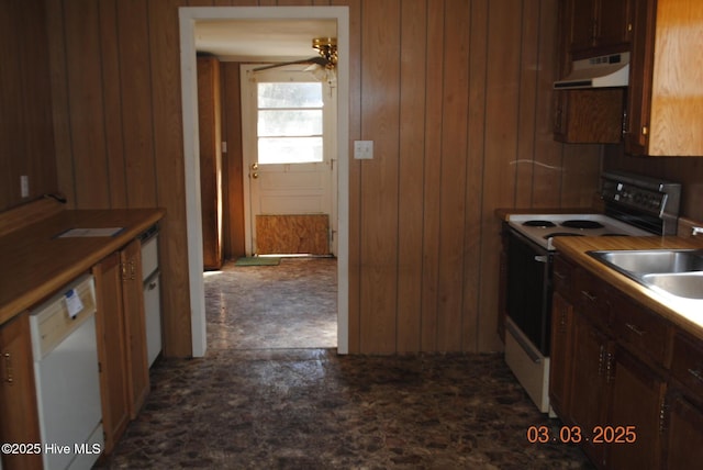 kitchen featuring under cabinet range hood, wood walls, white appliances, and a sink