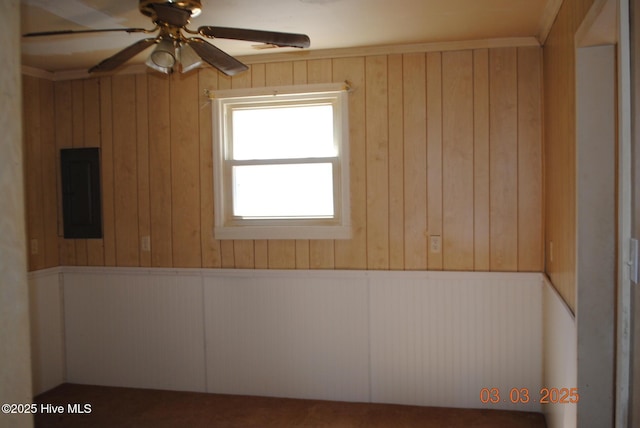 spare room with electric panel, wainscoting, and a ceiling fan