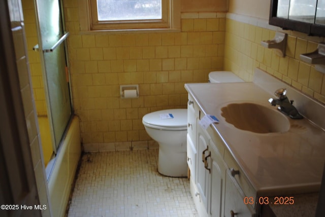 full bath featuring tile walls, toilet, tile patterned floors, vanity, and enclosed tub / shower combo