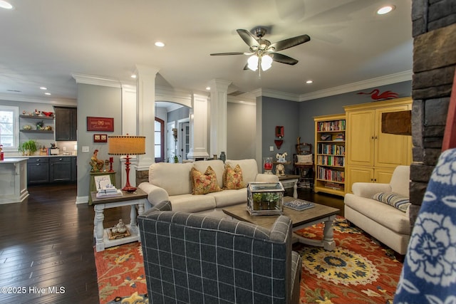 living area with decorative columns, arched walkways, ornamental molding, dark wood-style flooring, and recessed lighting