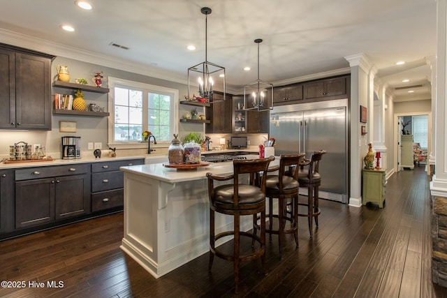 bar with visible vents, dark wood finished floors, hanging light fixtures, stainless steel built in fridge, and crown molding