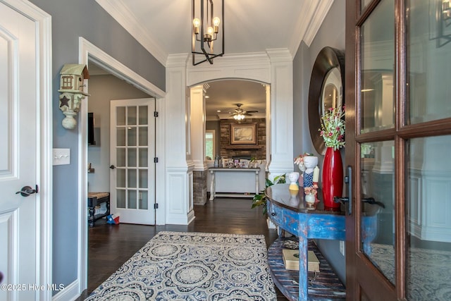 entryway featuring arched walkways, ceiling fan, ornamental molding, dark wood-type flooring, and ornate columns