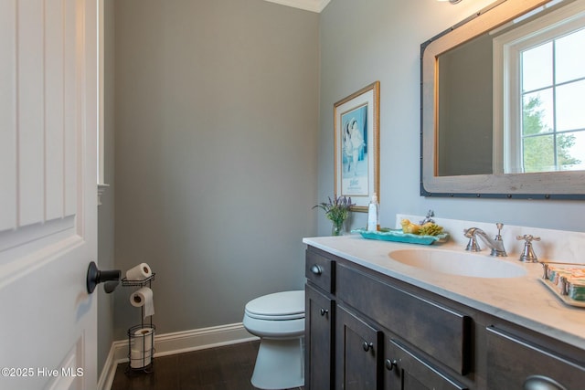 bathroom featuring baseboards, vanity, toilet, and wood finished floors