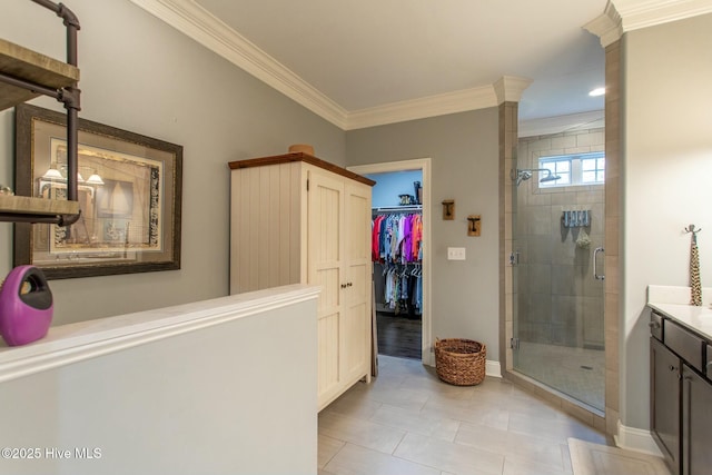 full bath featuring a stall shower, a walk in closet, crown molding, and vanity