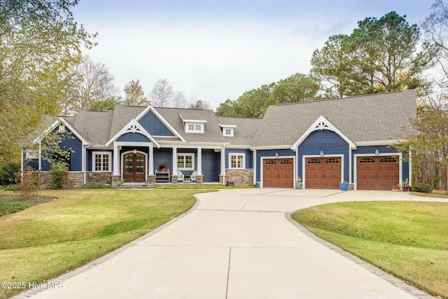 craftsman-style home featuring a shingled roof, concrete driveway, an attached garage, french doors, and a front lawn