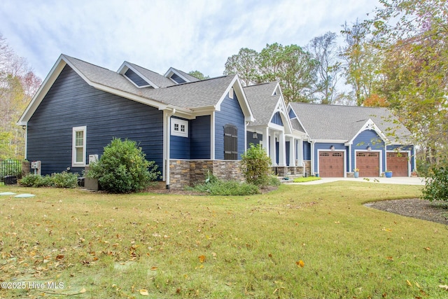 view of front of home with a garage, stone siding, concrete driveway, roof with shingles, and a front yard