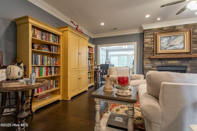 living area featuring a stone fireplace, recessed lighting, visible vents, ornamental molding, and dark wood finished floors