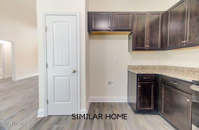 kitchen with baseboards, light stone countertops, dark brown cabinetry, and light wood-style floors