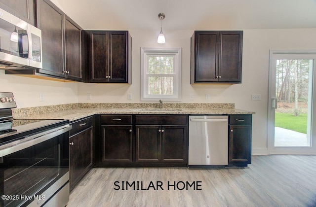 kitchen featuring stainless steel appliances, light wood-style flooring, a sink, and dark brown cabinetry