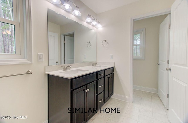 full bathroom featuring double vanity, tile patterned flooring, a sink, and baseboards