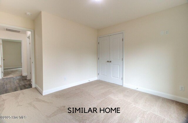 carpeted spare room with visible vents and baseboards