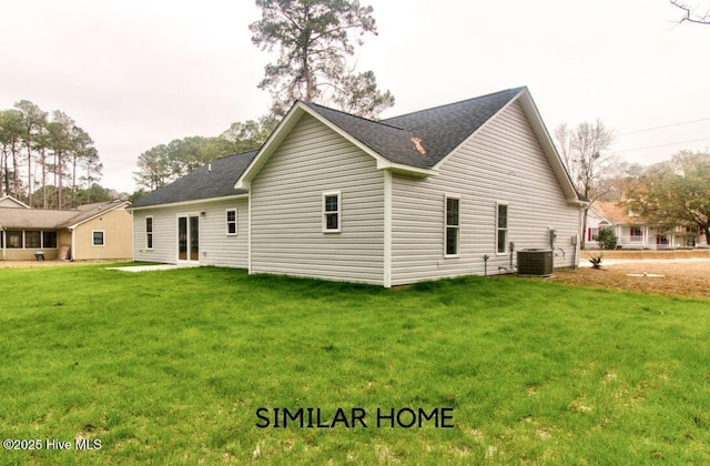 back of property featuring a shingled roof, central AC unit, and a lawn