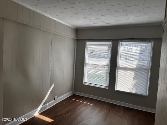 spare room featuring ornamental molding, dark wood finished floors, and baseboards